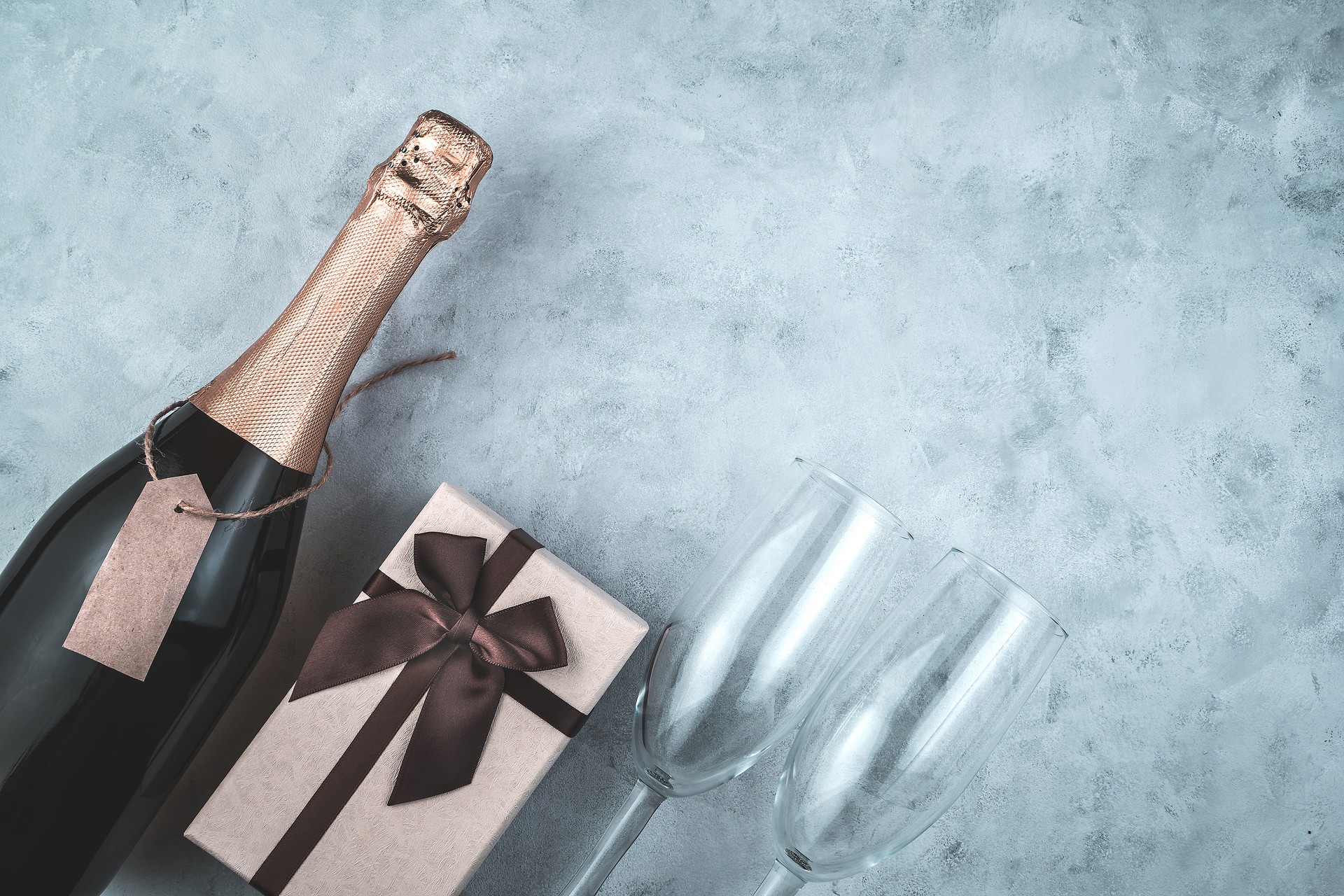 Gift box, alcohol and glasses on a gray background.